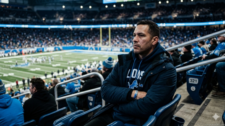 Detroit Lions fan standing in upper-deck stadium seating at night with arms folded, serious expression, cool blue stadium lighting, representing offseason stability and leadership continuity